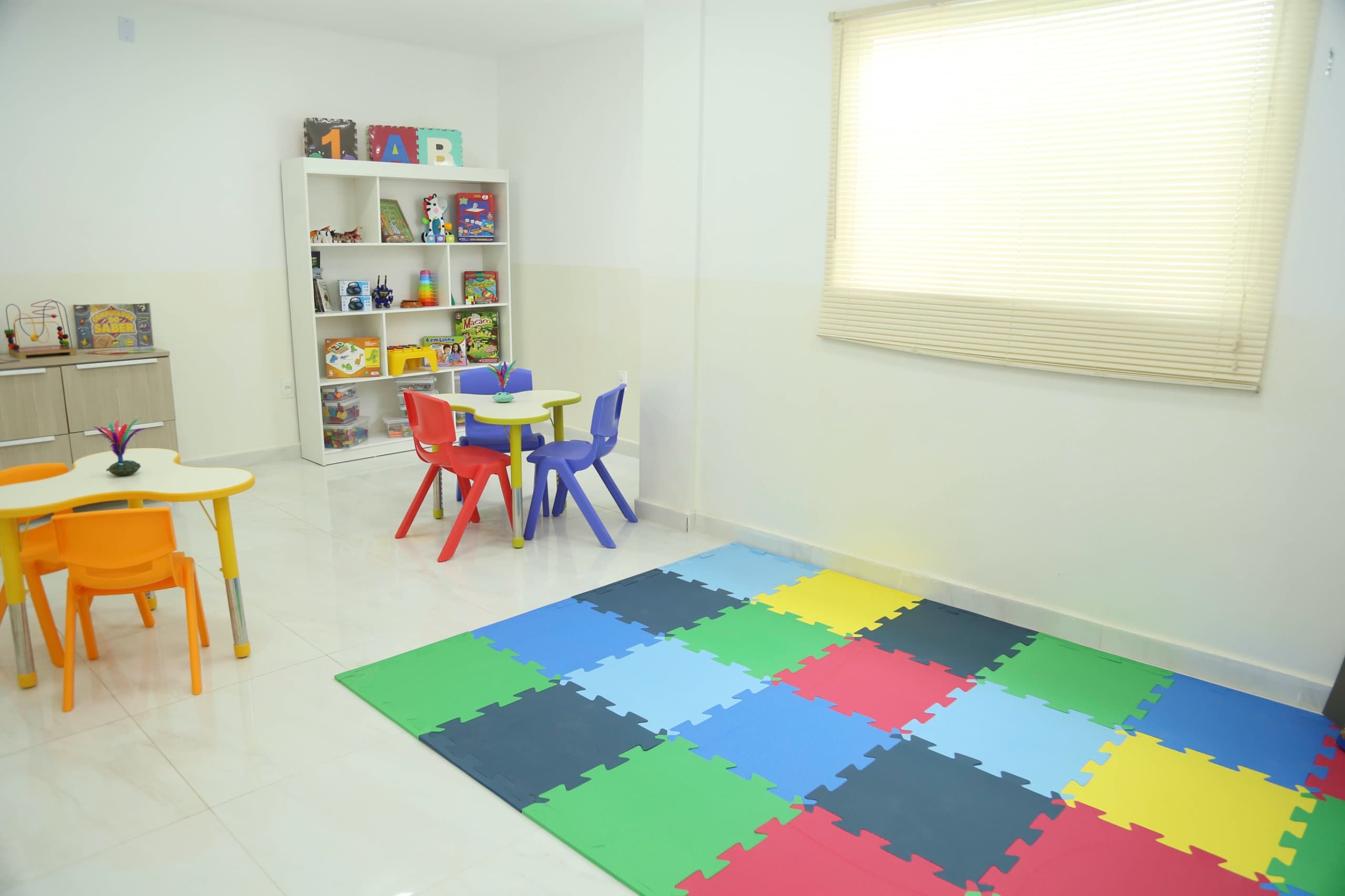 Sala infantil com brinquedos, mesas e tatame colorido