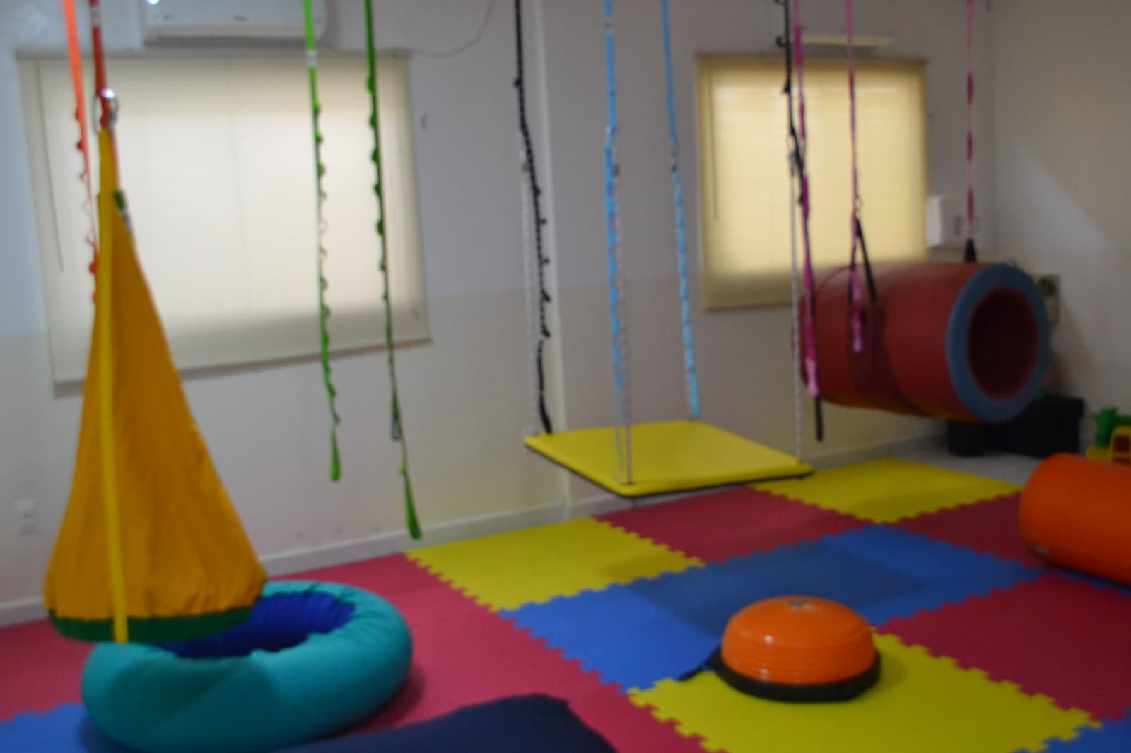 Sala sensorial com balanços e equipamentos coloridos